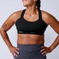 Athletic woman wearing GORUCK black sports bra and grey workout leggings, studio setting