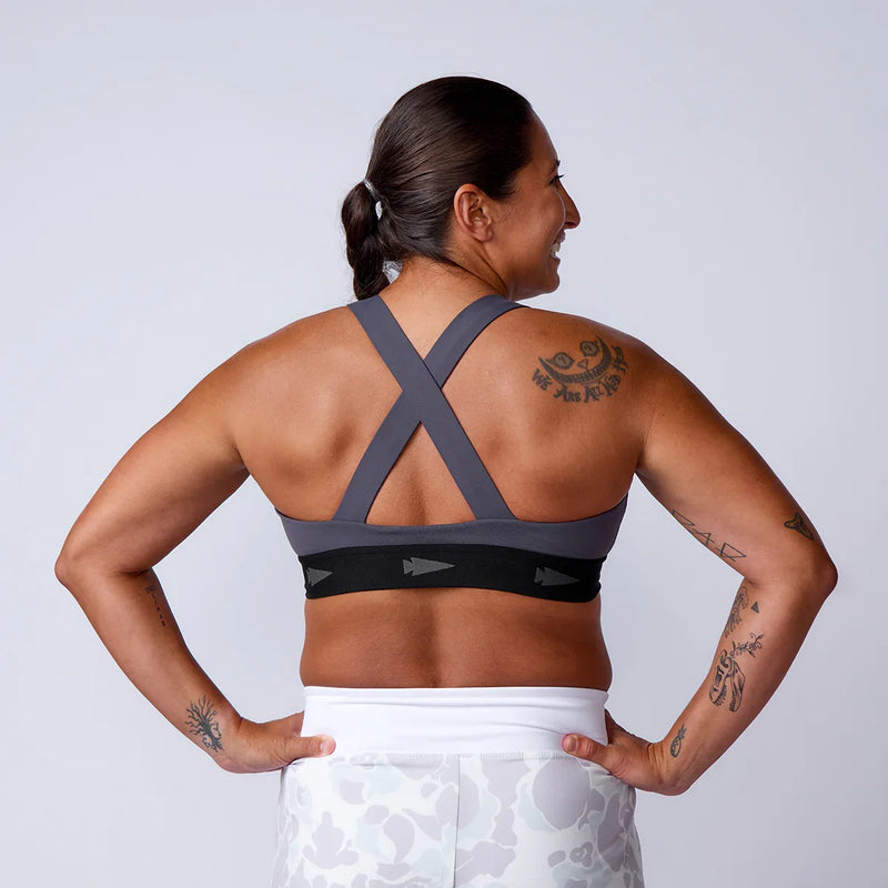Woman in athletic wear showing GORUCK sports bra with crossed back straps and arrow logo