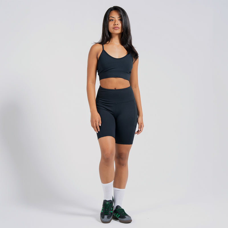 Women's black sports bra with racerback straps, worn with matching shorts