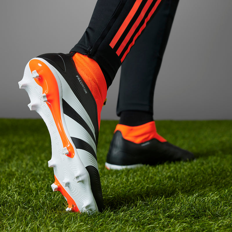 Soccer boot with black upper, white stripes, orange-red collar, and white/black studs