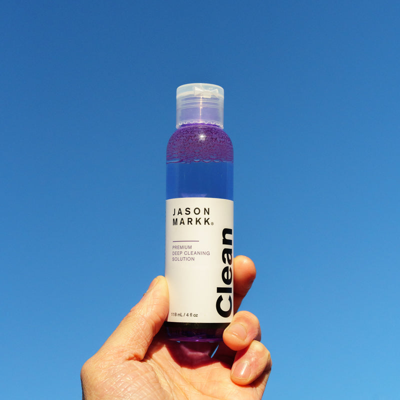 Shoe cleaner bottle held in hand, purple liquid, 4 fl oz, flip-top cap.