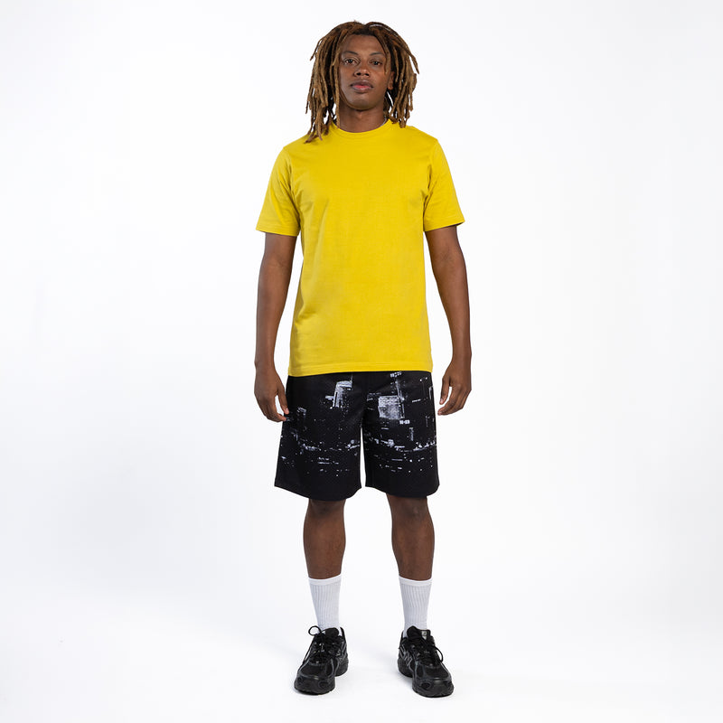 Men's black mesh shorts with white skyline print; full-body view with yellow T-shirt