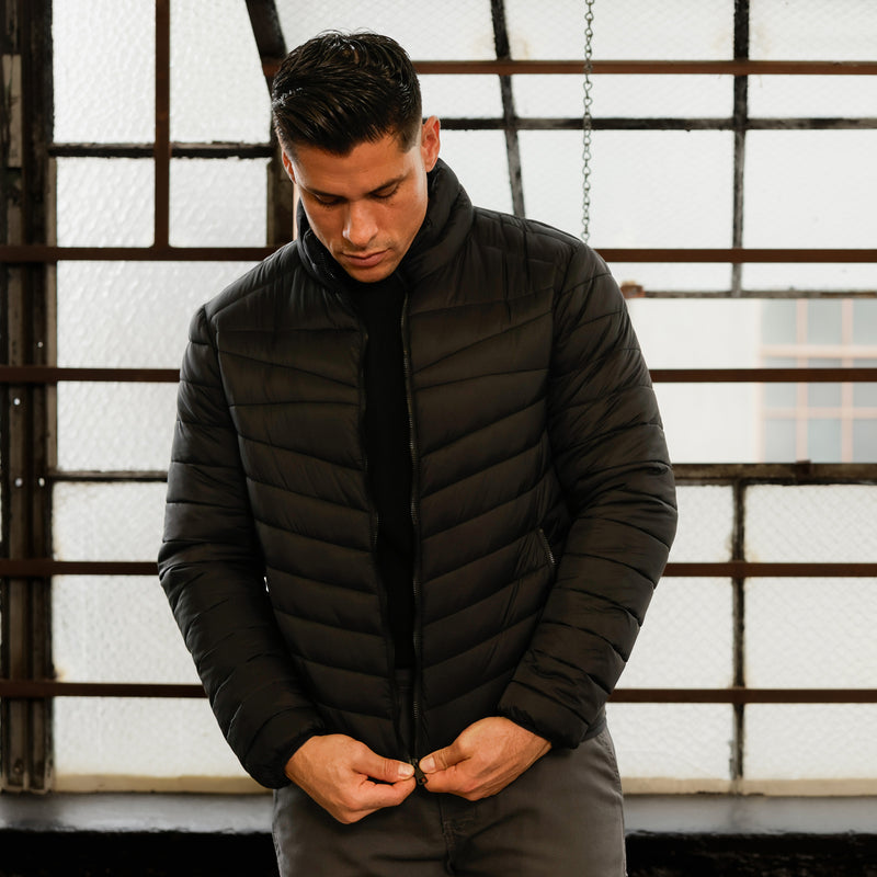 Men's black puffer jacket with stand collar and zip pull detail, quilted front