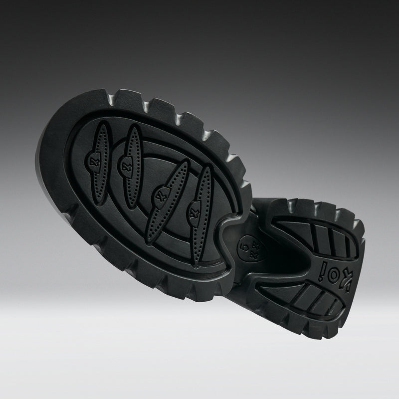 Black rubber sole of a shoe on a gradient gray background