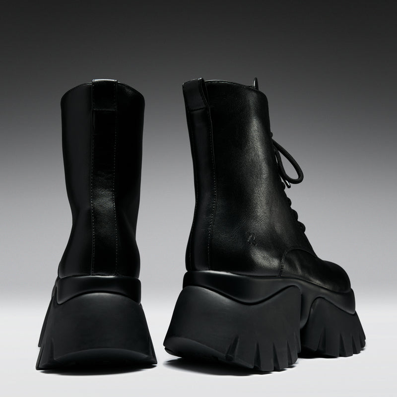 Pair of black platform boots on a gradient background