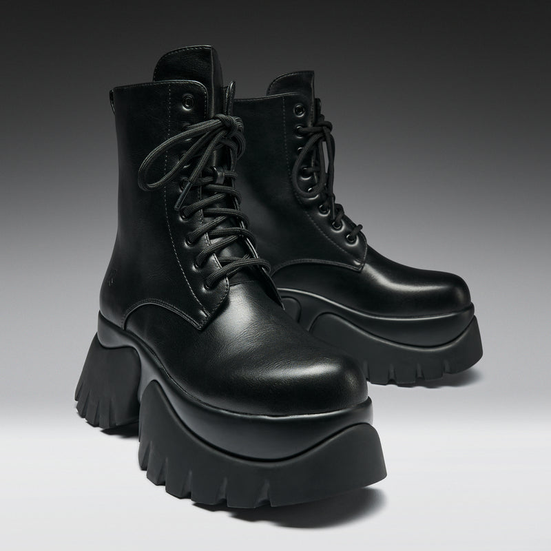 Black platform boots on a gradient background