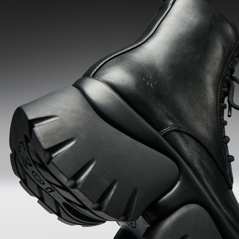 Close-up of a black boot with a thick sole on a gradient background