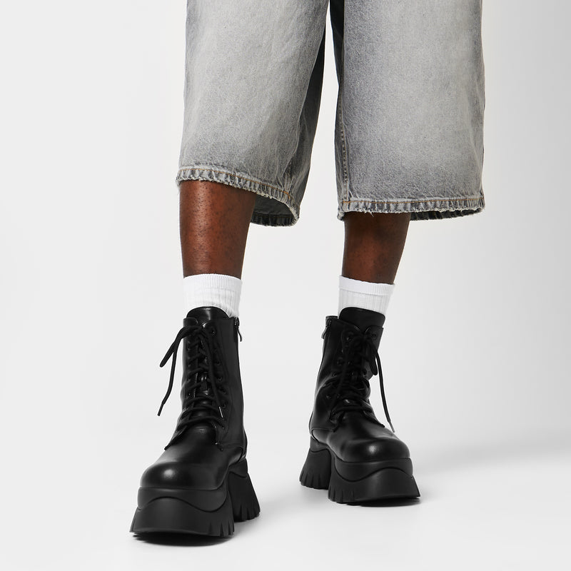 A model wearing gray denim shorts and black lace-up boots with a chunky sole.