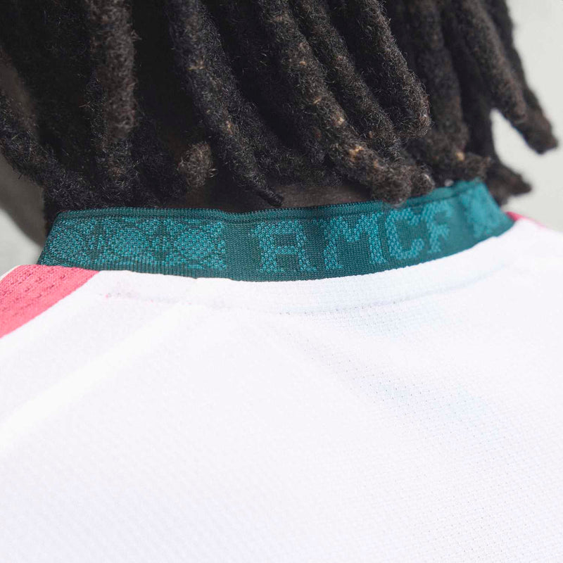 White jersey collar with teal ribbed trim and sponsor wordmark band
