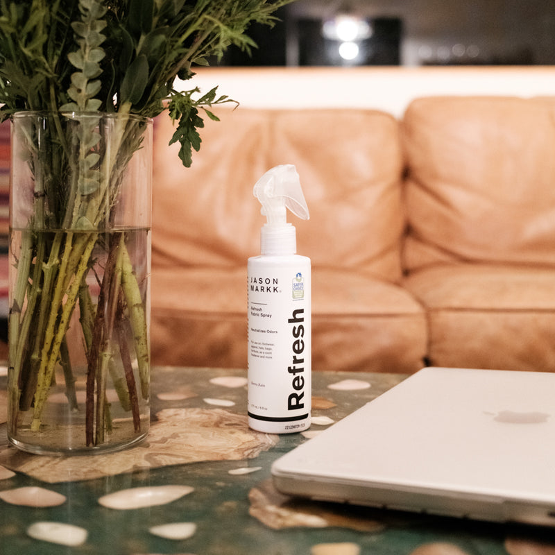 Jason Markk Refresh fabric spray bottle on a table near a notebook