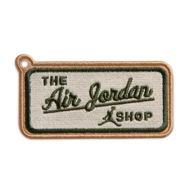 Embroidered fabric patch reading "The Dry Goods Shop" with brown border