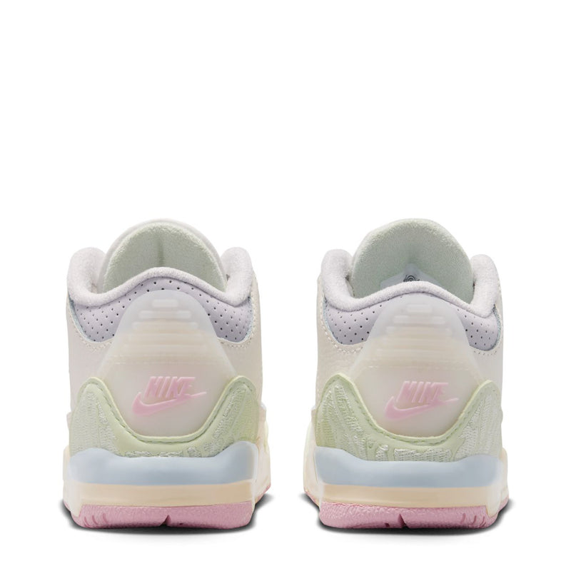 Toddler white sneaker with heel pull tab, green side trim, and pink-blue midsole