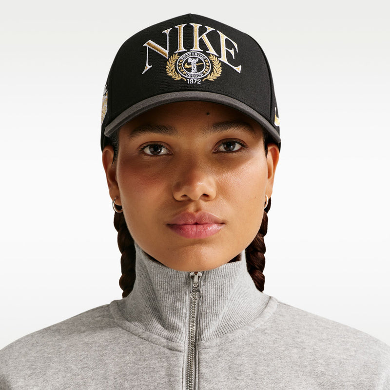 Black structured Nike cap with curved bill and front crest logo, worn with hoodie
