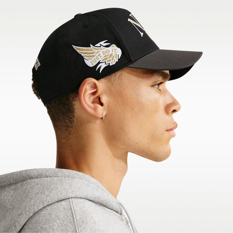Black snapback cap with curved bill and side wing logo embroidery