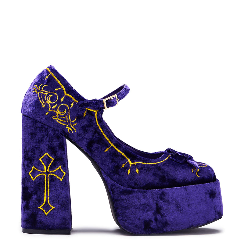A purple velvet platform heel with gold embroidery, including a cross and floral details, with a chunky heel and ankle strap.