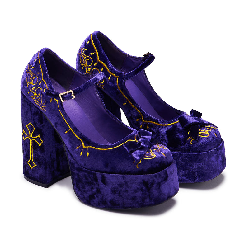 A purple velvet platform heel with gold embroidery, including a cross and floral details, with a chunky heel and ankle strap - 3/4 view