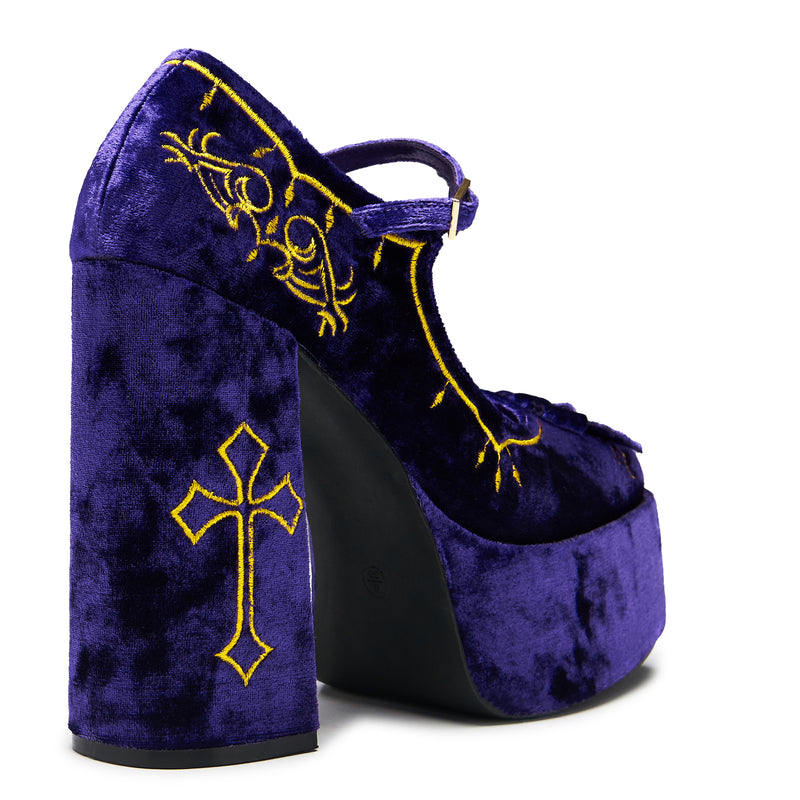 A purple velvet platform heel with gold embroidery, including a cross and floral details, with a chunky heel and ankle strap - back 3/4 view