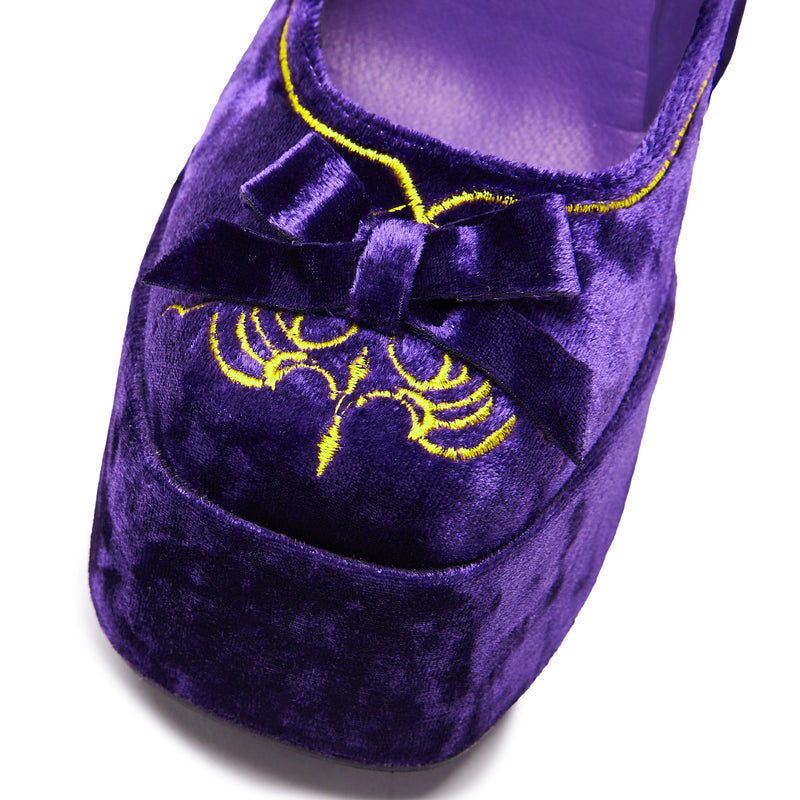 A purple velvet platform heel with gold embroidery, including a cross and floral details, with a chunky heel and ankle strap - front detail