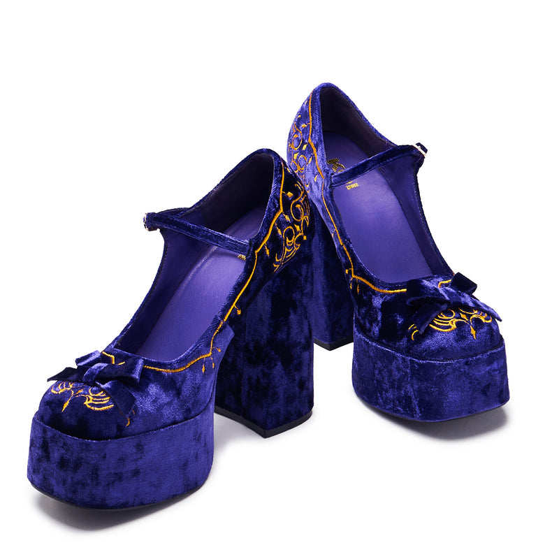 A purple velvet platform heel with gold embroidery, including a cross and floral details, with a chunky heel and ankle strap - front and 3/4 view