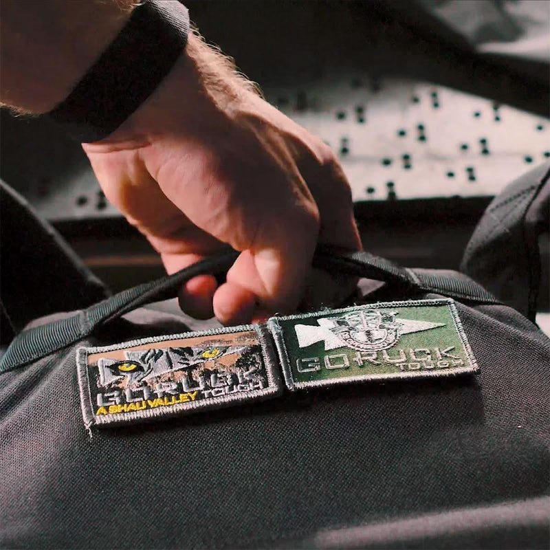 Hand gripping GORUCK backpack handle with GORUCK Tough gear patches attached