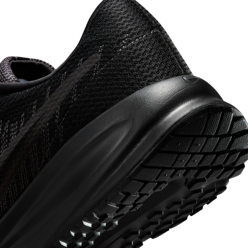 Men's black running shoe close-up of sidewall and tread studs along outsole.