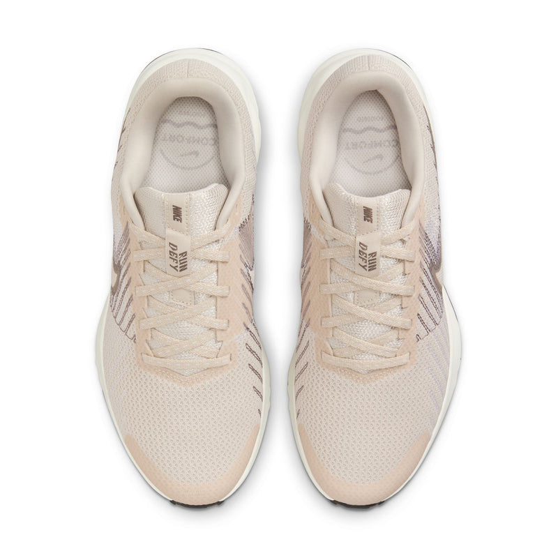 Pair of light beige women's running shoes with lace-up closure and cushioned collars.