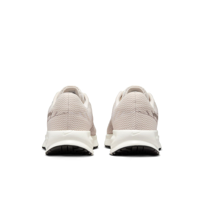 Pair of light beige women's running shoes showing rear heel and black traction outsole.