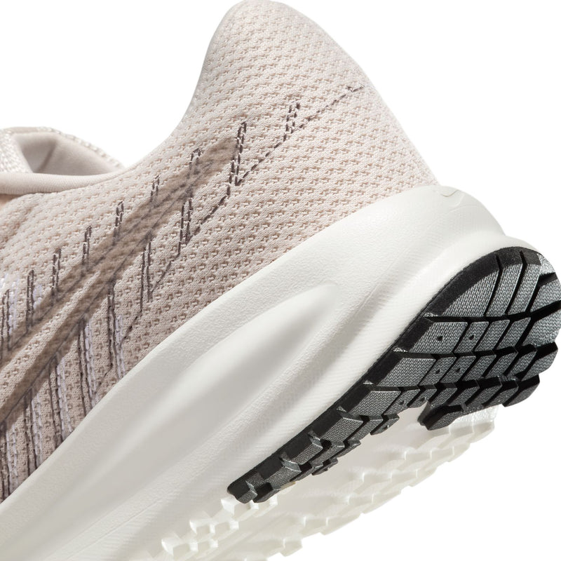 Light beige women's running shoe close-up of heel midsole and black tread pattern.