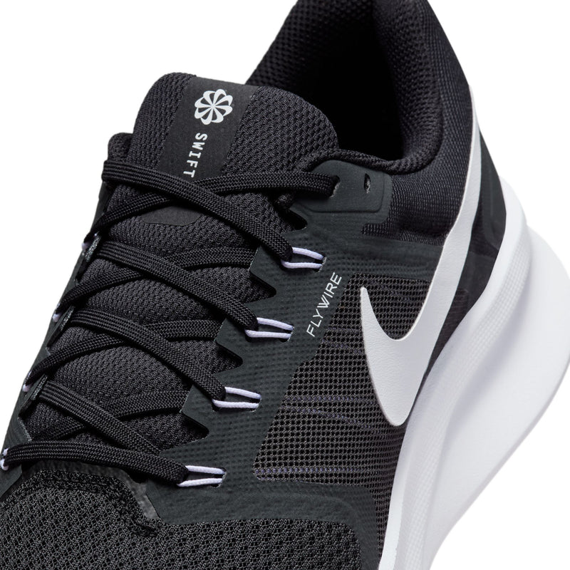 Close-up of men's black knit running shoe upper with lace webbing and white Swoosh.