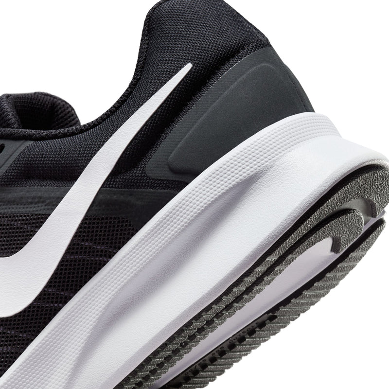 Close-up of black running shoe side with white Swoosh and textured midsole edge.