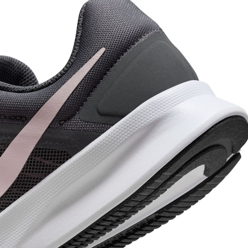 Close-up of dark gray running shoe midsole: white foam with pink-lilac side trim