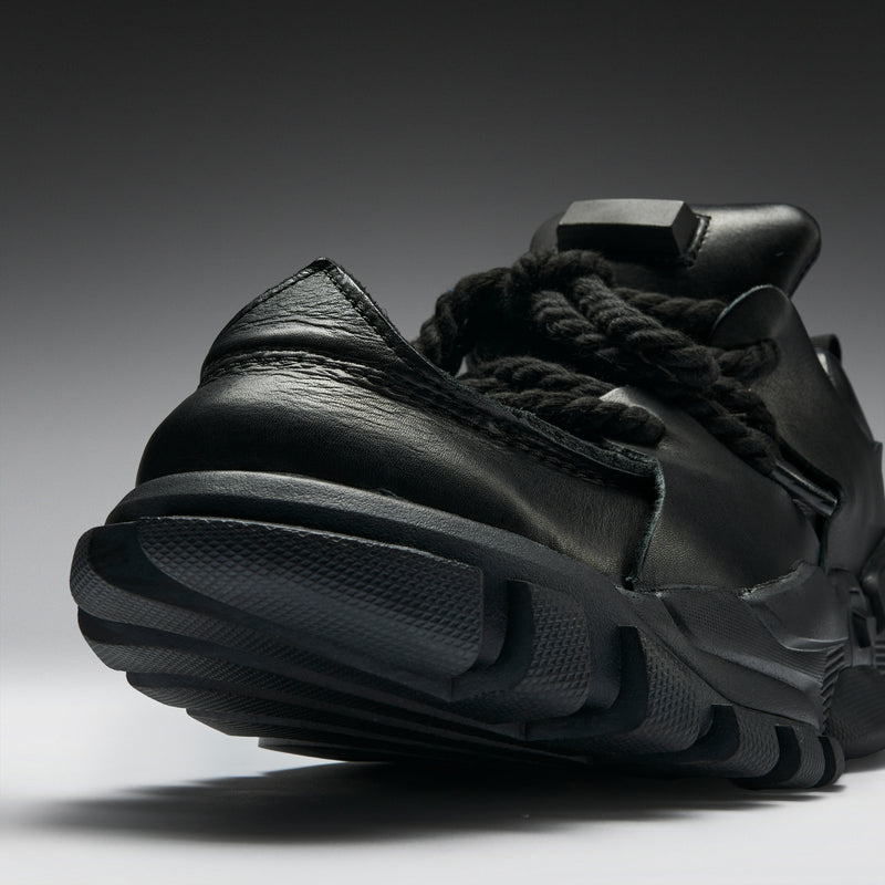 Black sandal with thick sole on a gradient background