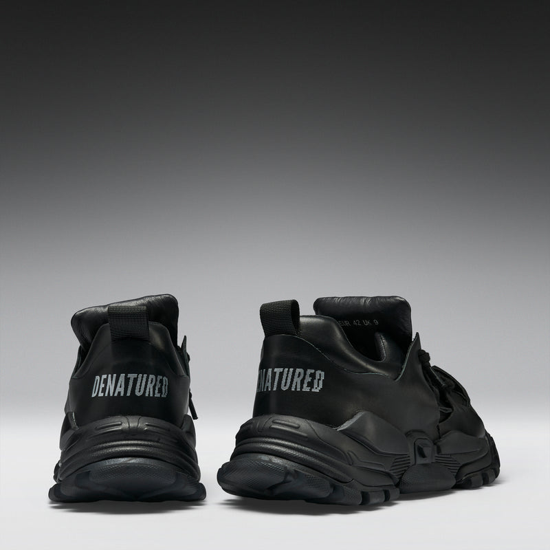 Black sneakers with 'DENATURED' branding on a gradient background