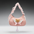 Pink handbag with teddy bear charm on a gray background