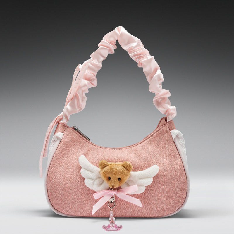 Pink handbag with teddy bear charm on a gray background