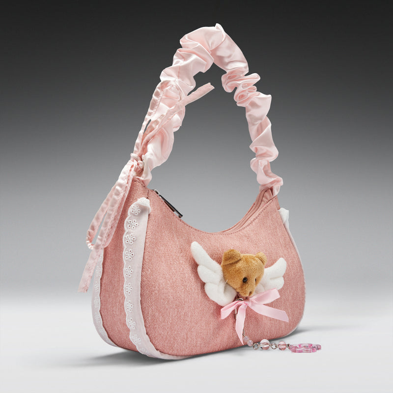 Pink handbag with a teddy bear charm on a gray background