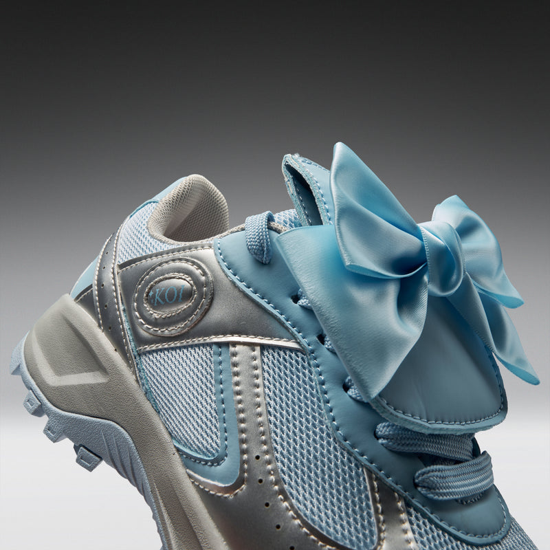Blue and gray sneaker with a large bow on a gradient background