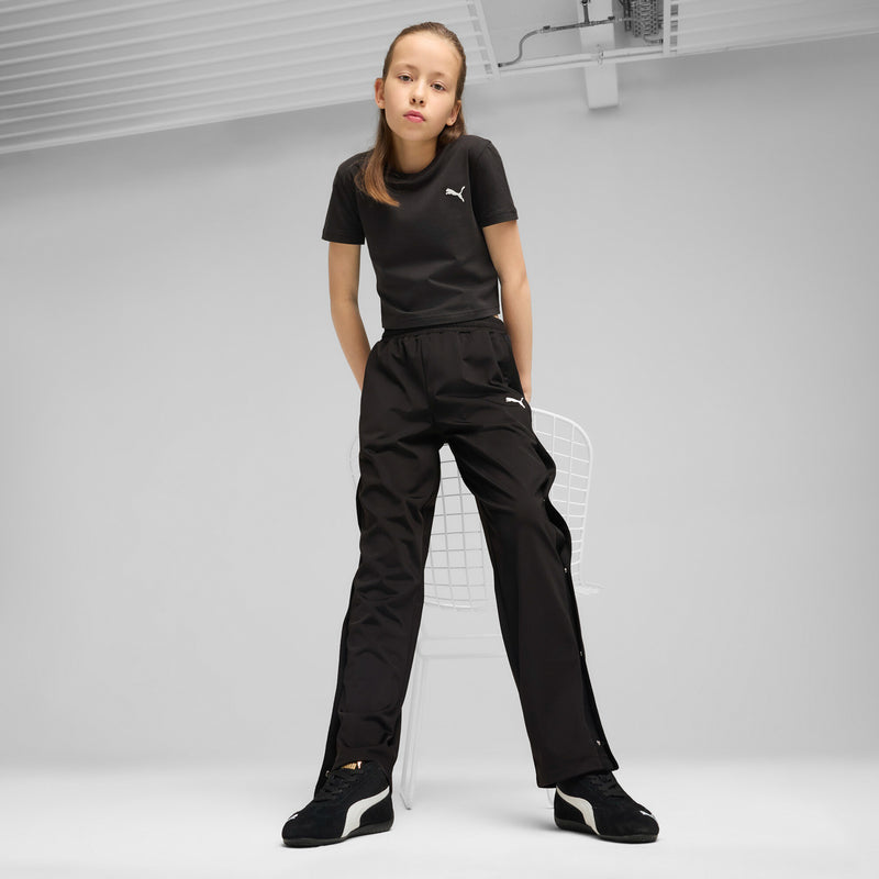 Youth Puma sneakers on feet with black pants and white sock accents