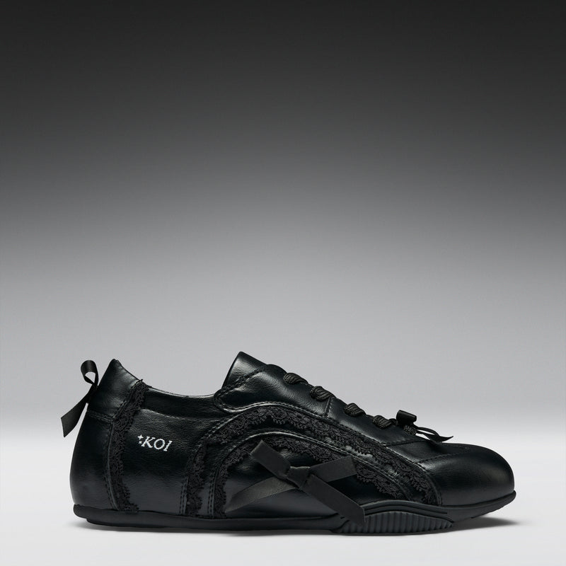 Black sneaker with bow designs on a gray background