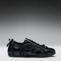 Black sneaker with bow designs on a gray background