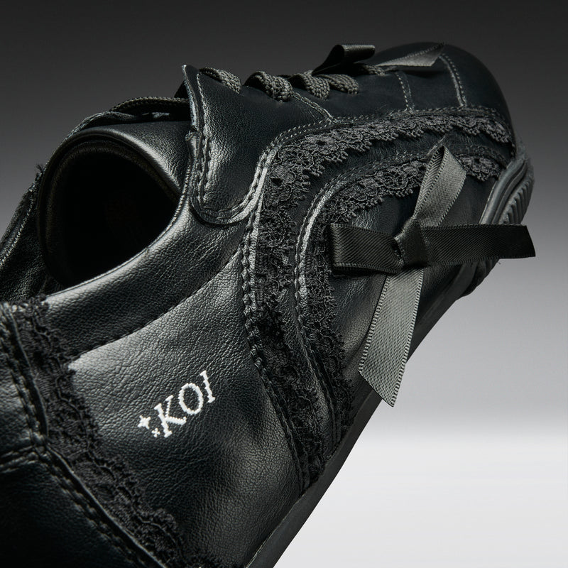 Black leather shoe with lace details and 'Koi' branding on a gradient background