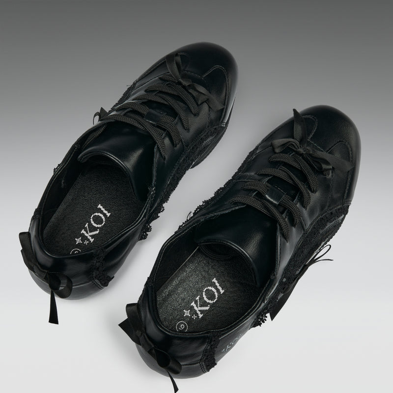 Pair of black sneakers with 'KOI' branding on a gradient background