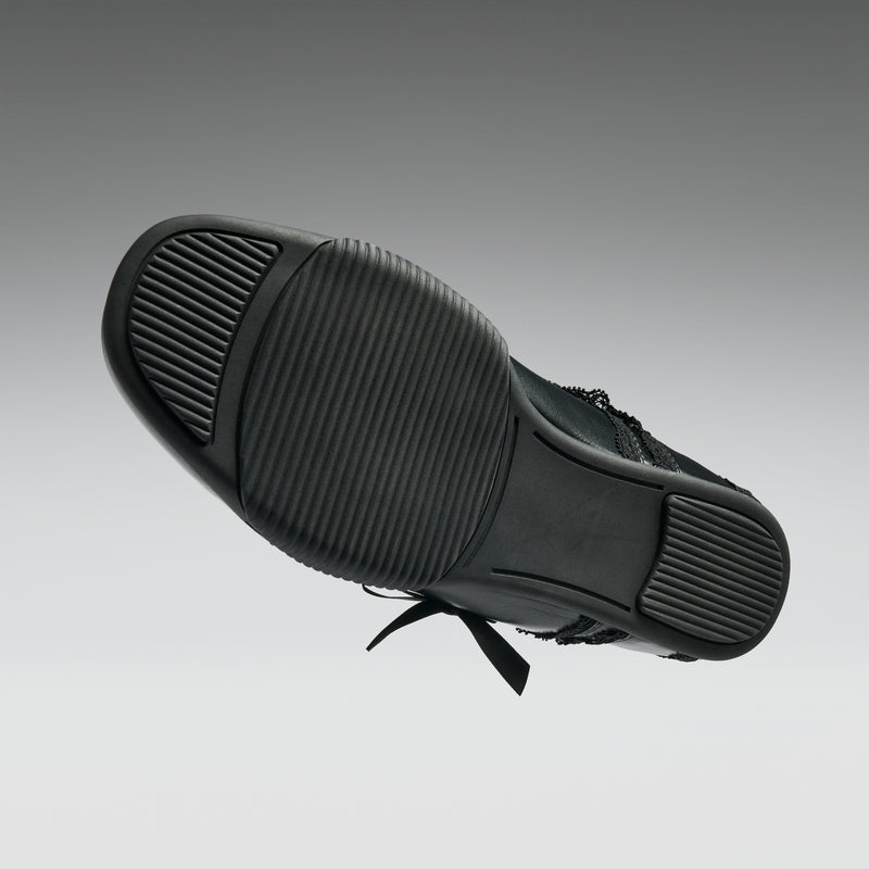 Black sneaker with a focus on sole texture on a gray background