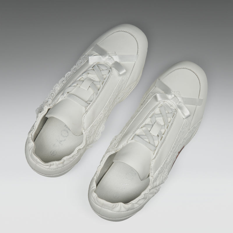 White sneakers with lace details on a light gray background