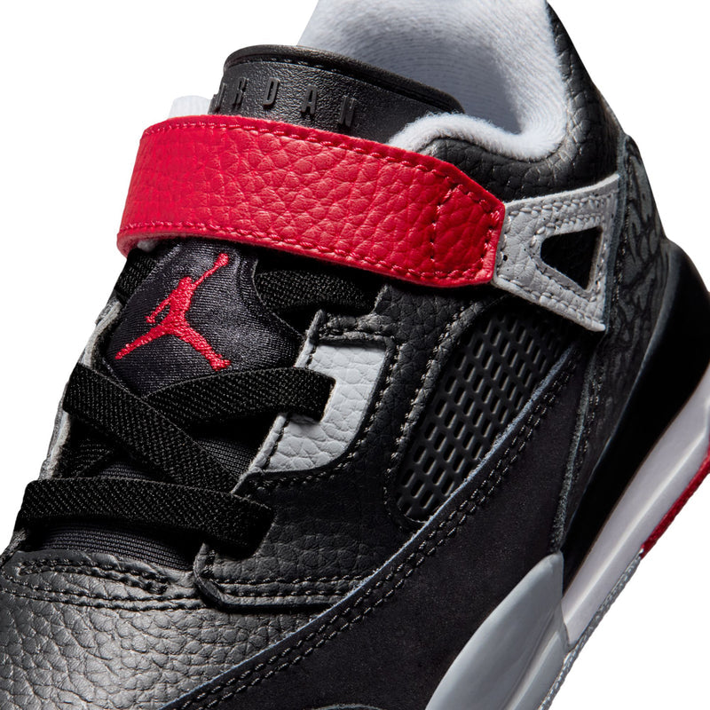 Kids low-top sneaker close-up: black leather panels with red collar strap and gray lace area
