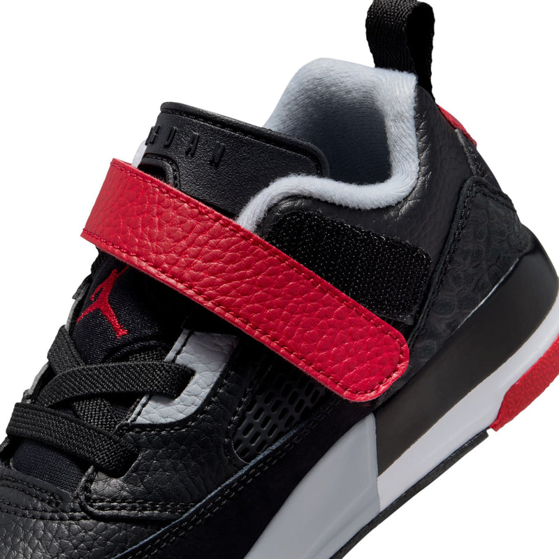 Kids low-top sneaker close-up: black upper with textured red strap and white midsole