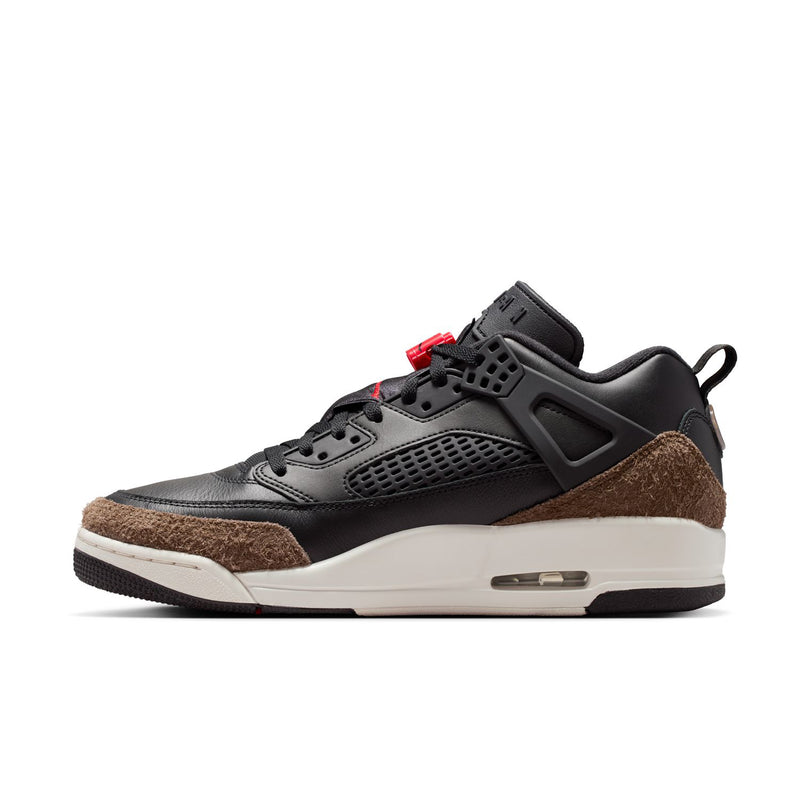 Black low-top sneaker with red lace accents, brown suede side panel, white midsole