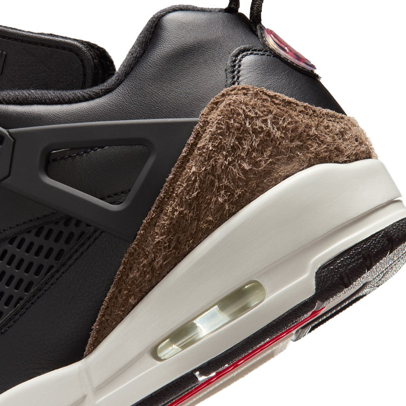 Close-up of black sneaker midsole with brown suede trim and clear air window