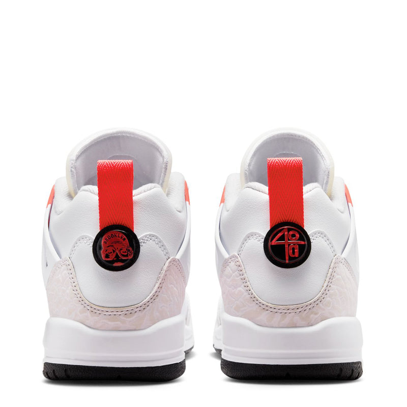 Back view of youth white sneakers with red heel tabs and round logo details