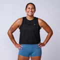 Smiling woman in GORUCK black tank top and blue shorts, studio fitness apparel photo